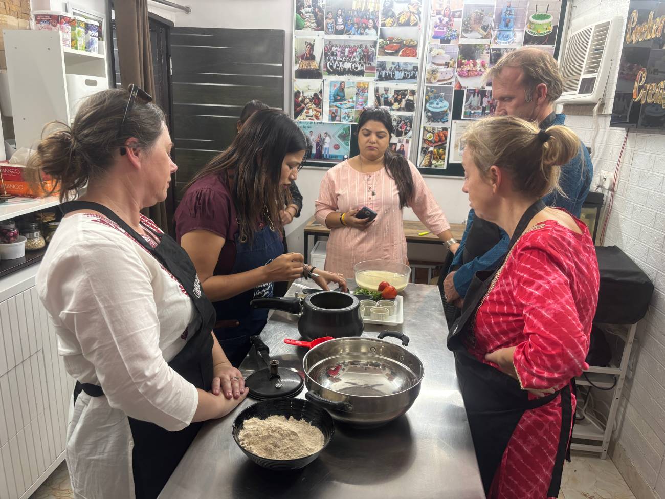 Travelers participating in an authentic Indian home kitchen experience in Agra, learning traditional cooking from a local Indian woman during a cultural inclusion activity.
