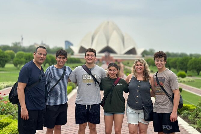 A family group posing for a photo in front of the Lotus Temple in Delhi during their Golden Triangle sightseeing tour
