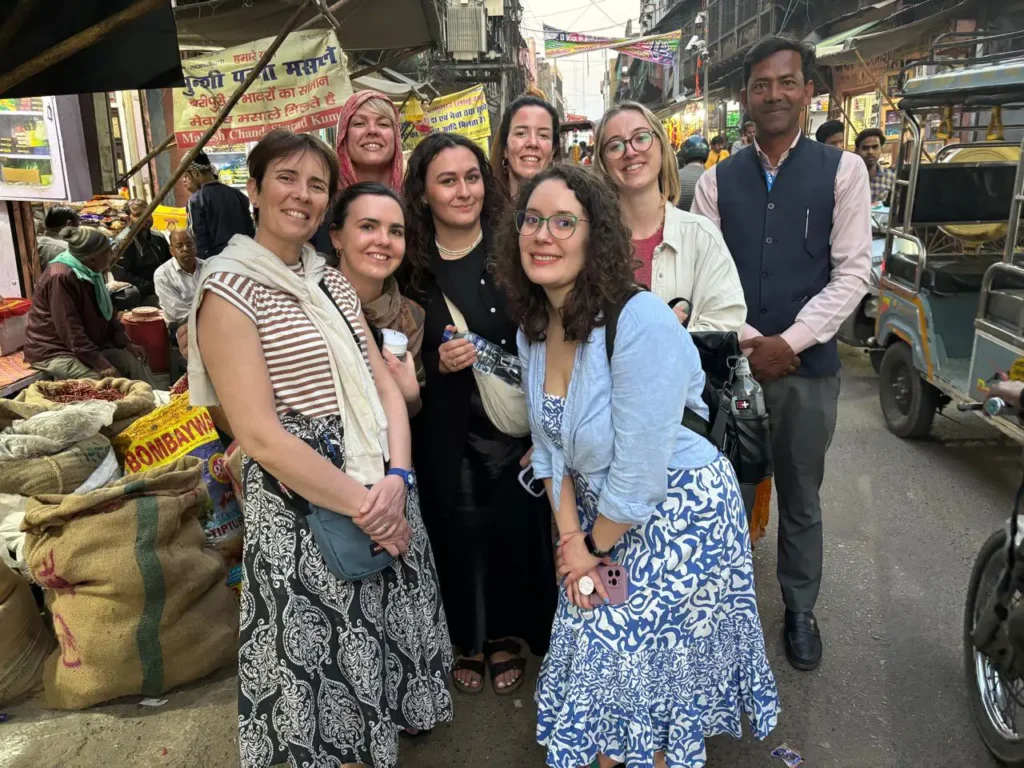 International female tourists with tour guide Anjum Saeed exploring a busy local market in Agra, India, during a guided shopping and cultural tour.