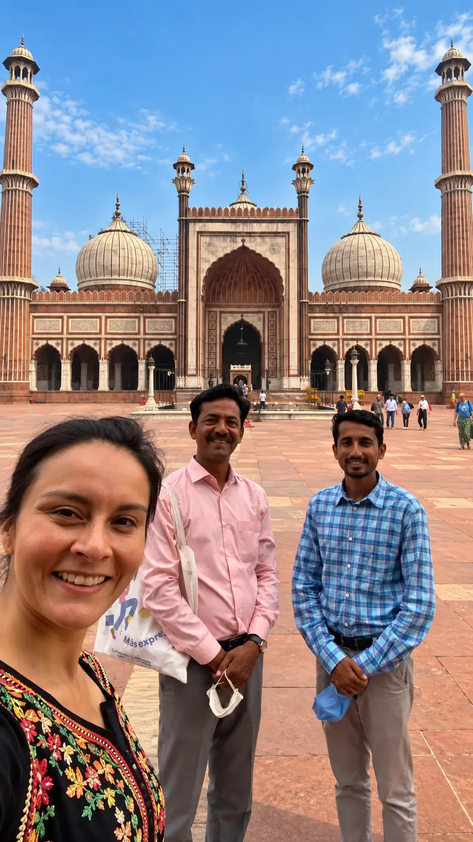 Solo female tourist posing with two male tour guides at Jama Masjid in Delhi, India.