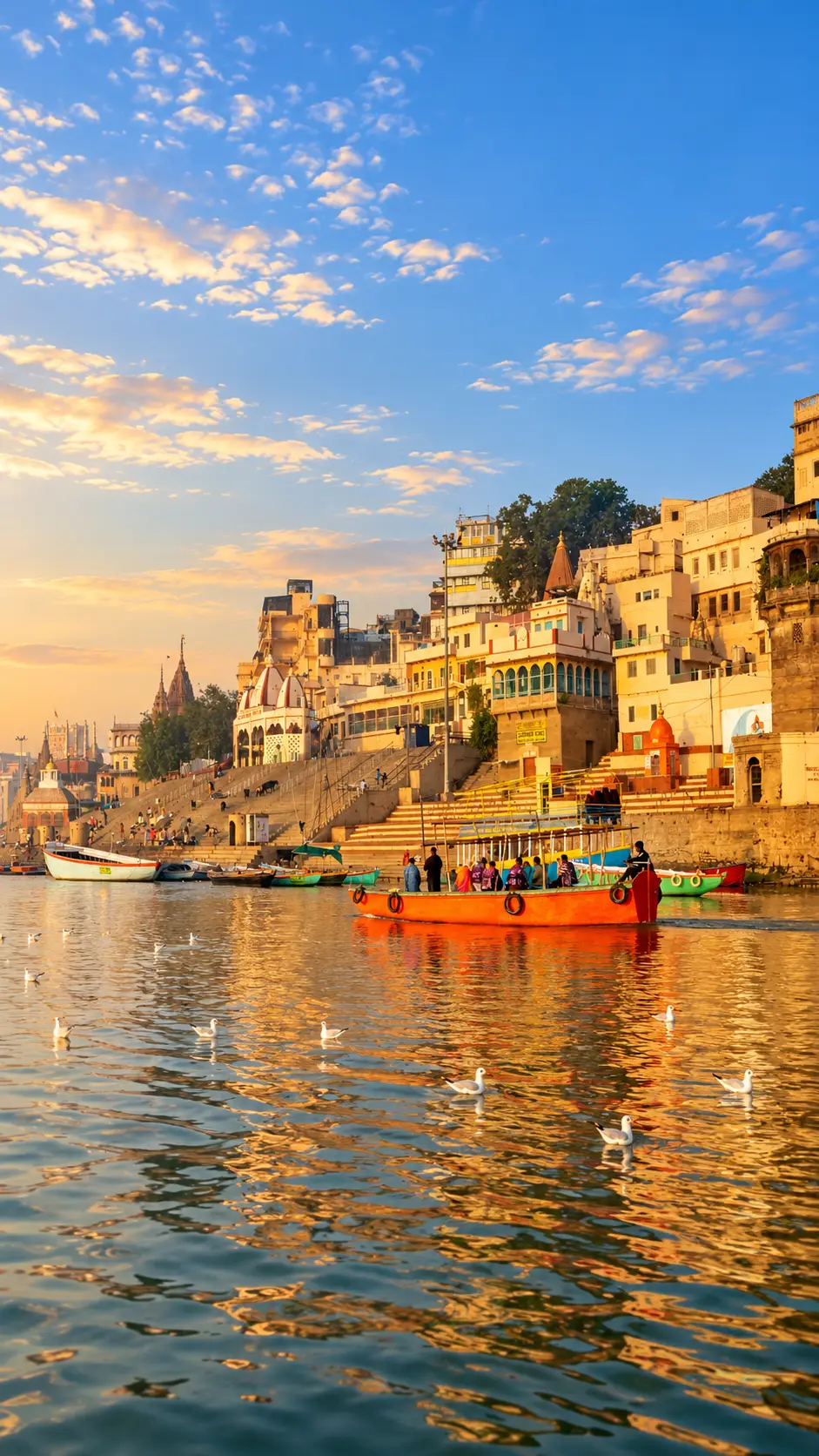 Colorful boats on the Ganges River with the historic ghats of Varanasi illuminated at golden hour.