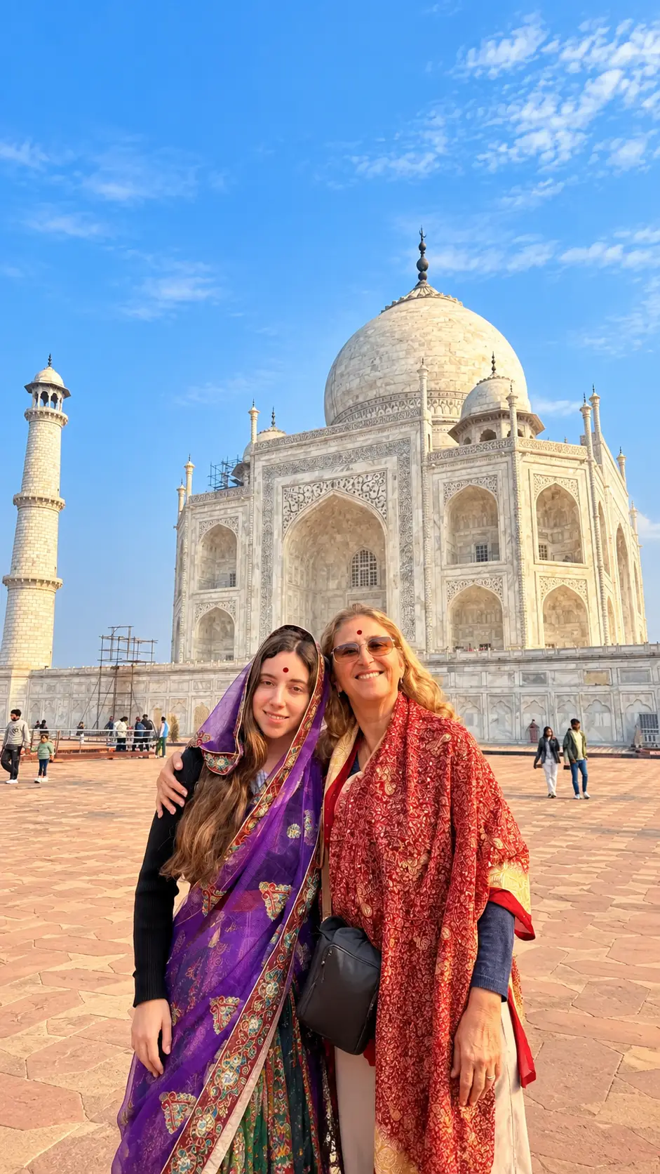 Two female tourists posing in front of the Taj Mahal in Agra, India.
