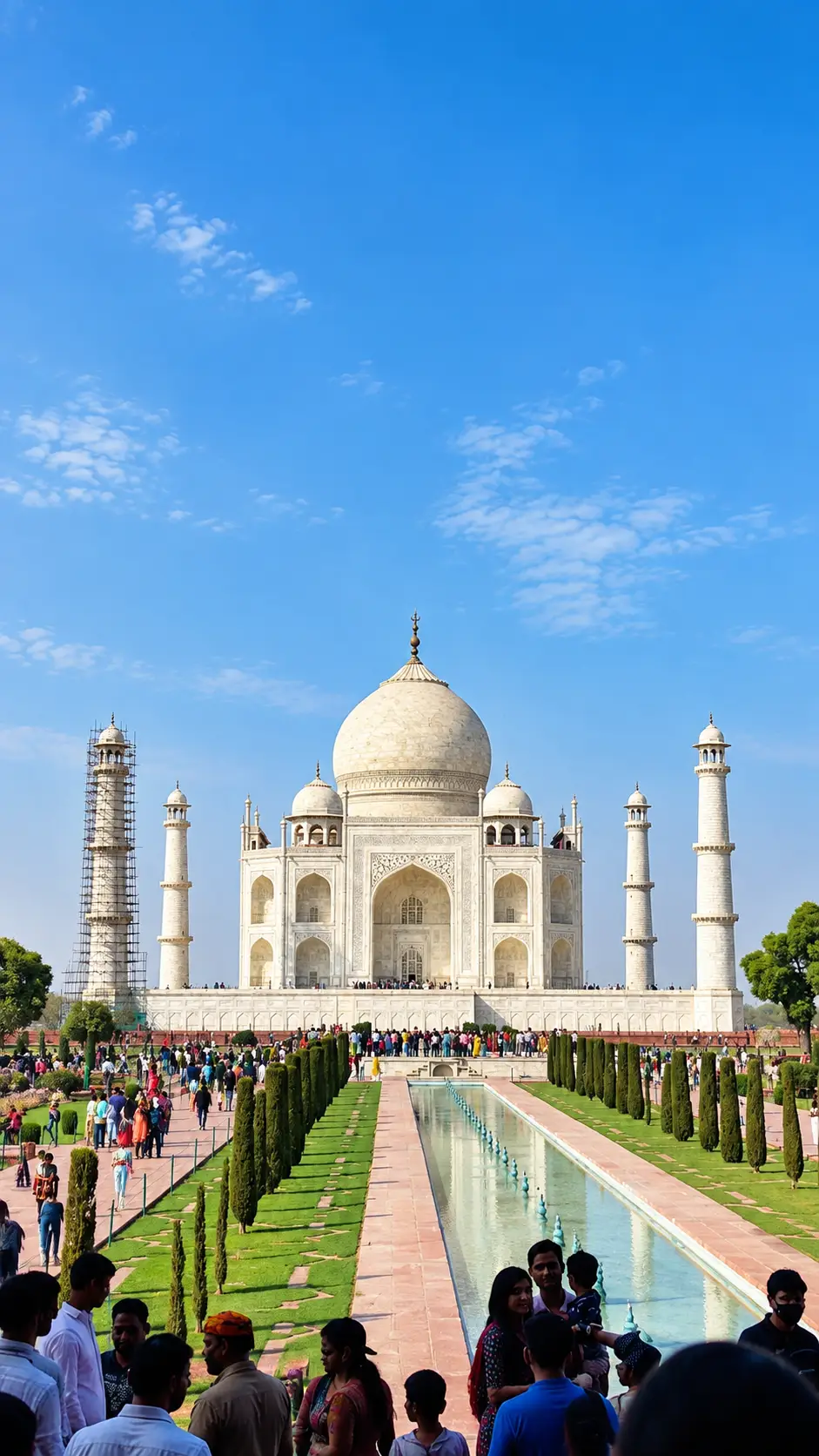 Taj Mahal in Agra viewed from the garden with tourists and reflecting pool under a blue sky