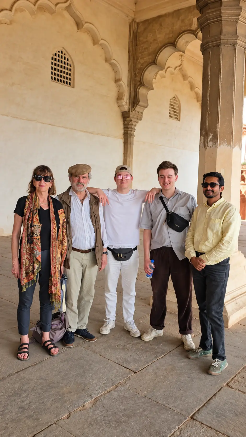 Tour guide Riyaz Khan with four tourists beneath ornate Mughal arches at a historic monument in Agra