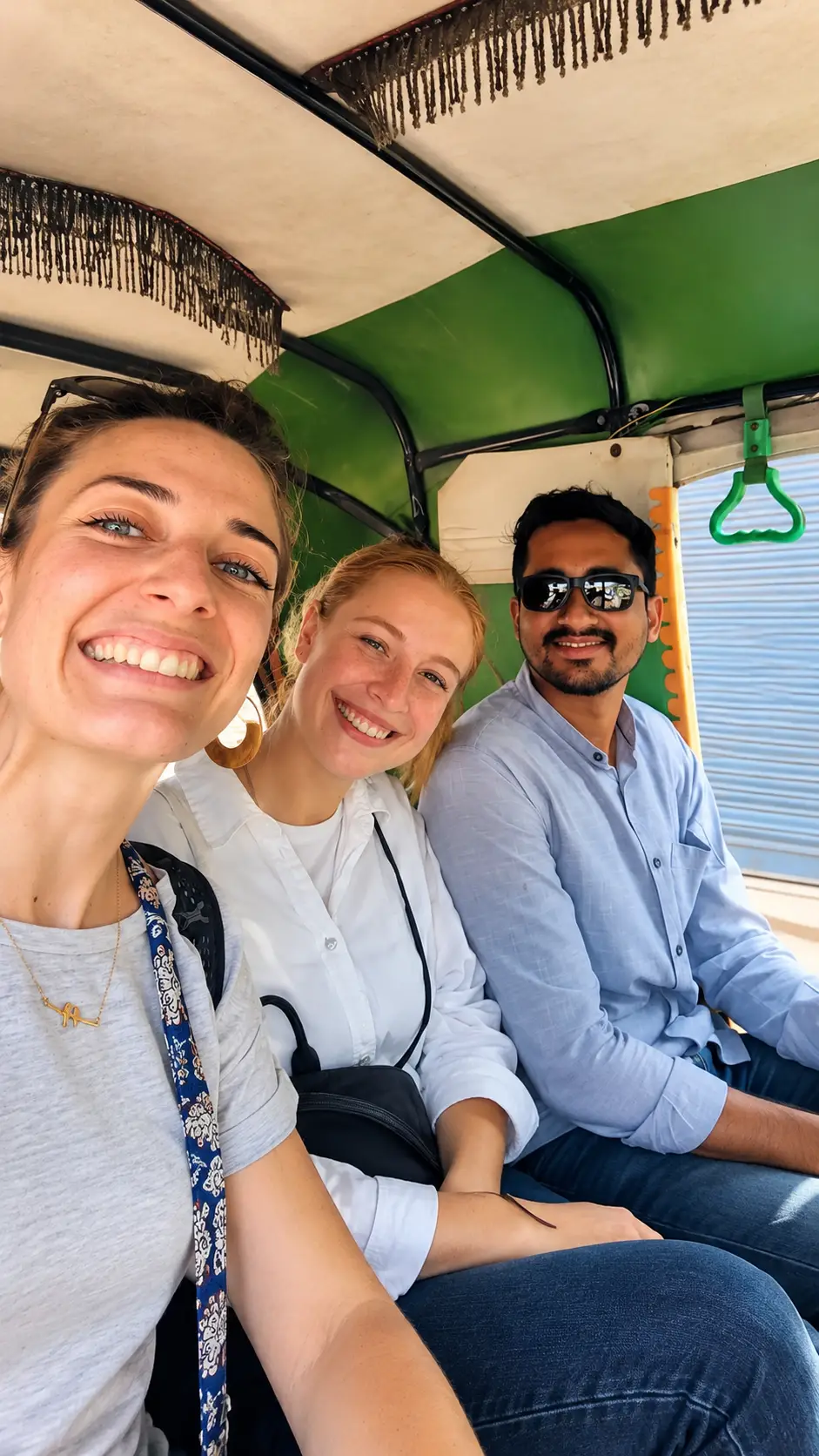 Two female tourists taking a selfie with tour guide Riyaz Khan inside an auto rickshaw in India.