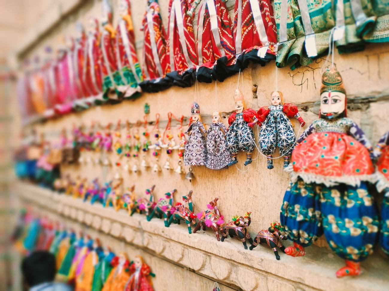 Colorful Rajasthani Kathputli puppets and traditional handicrafts displayed for sale in a local market in Jaisalmer, Rajasthan, India.