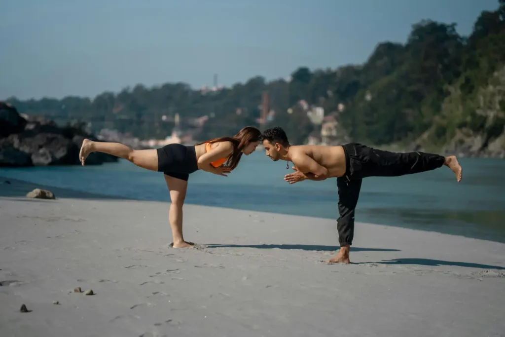 Complete India Golden Triangle Tour Guide - A Journey Through India's Most Iconic Destinations 6 Couple doing yoga practice on bank of ganga river Ram Jhula Swarg Ashram Rishikesh Uttarakhand India