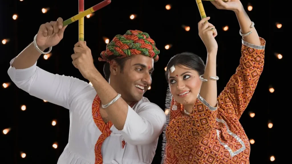A man and woman in traditional Gujarati attire performing Dandiya Raas during the Navratri festival, celebrating India's vibrant folk dance and cultural heritage.