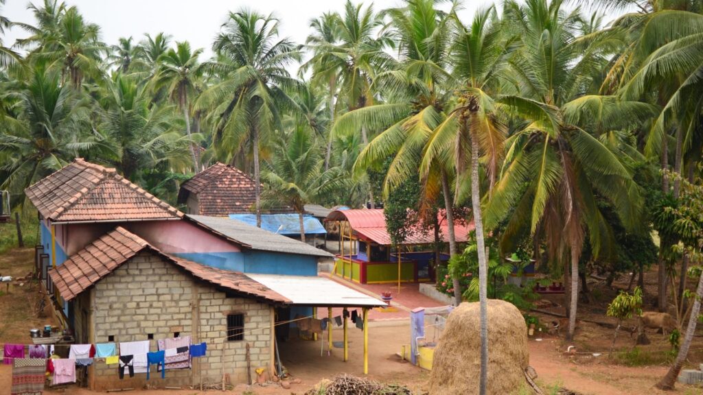 Traditional Indian village with tiled-roof houses surrounded by coconut palm trees, showcasing rural life, local architecture, and India's cultural heritage.